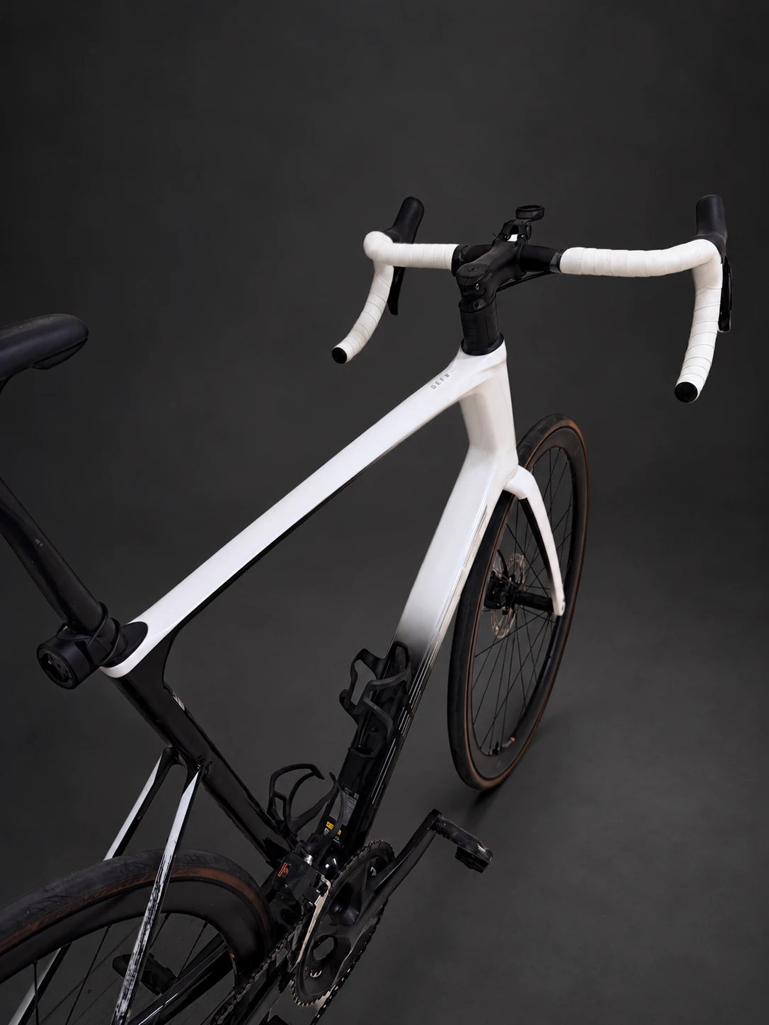Original white and black road bike without added graphics, seen from above against a graphite background.